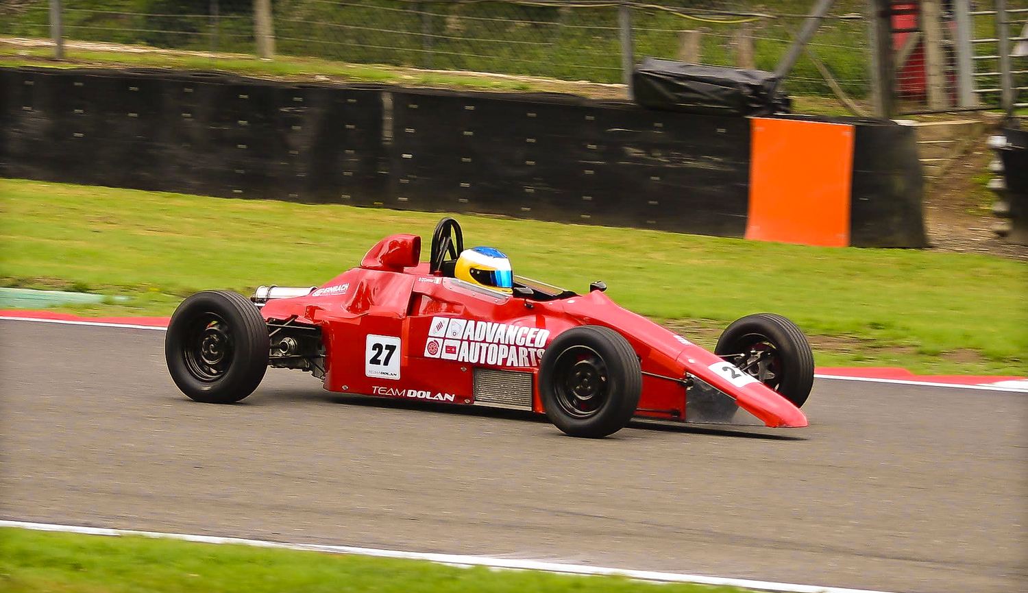Red single-seater race car cornering on a race track, motorsport photography