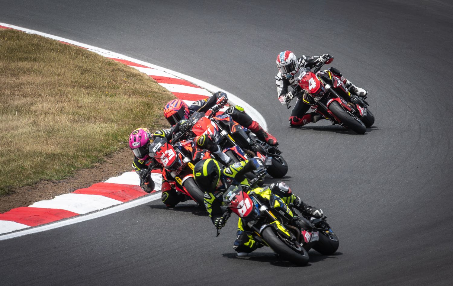 Group of motorcycle racers cornering together, motorsport photography