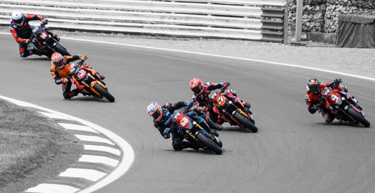 Black and white photo of motorcycle racers cornering in formation, motorsport photography