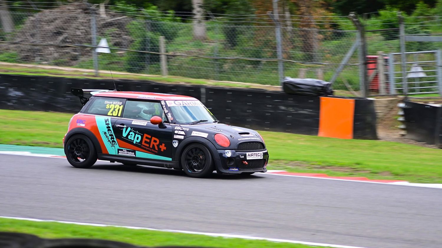 Liveried Mini race car cornering on track, motorsport photography