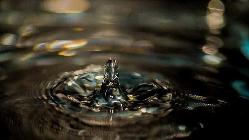 Macro photo of a water droplet crown splash on dark water, nature photography