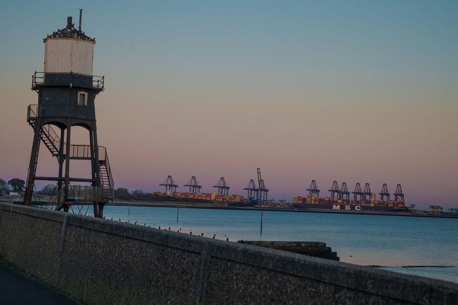 Lighthouse tower with dock cranes at dusk wall art print