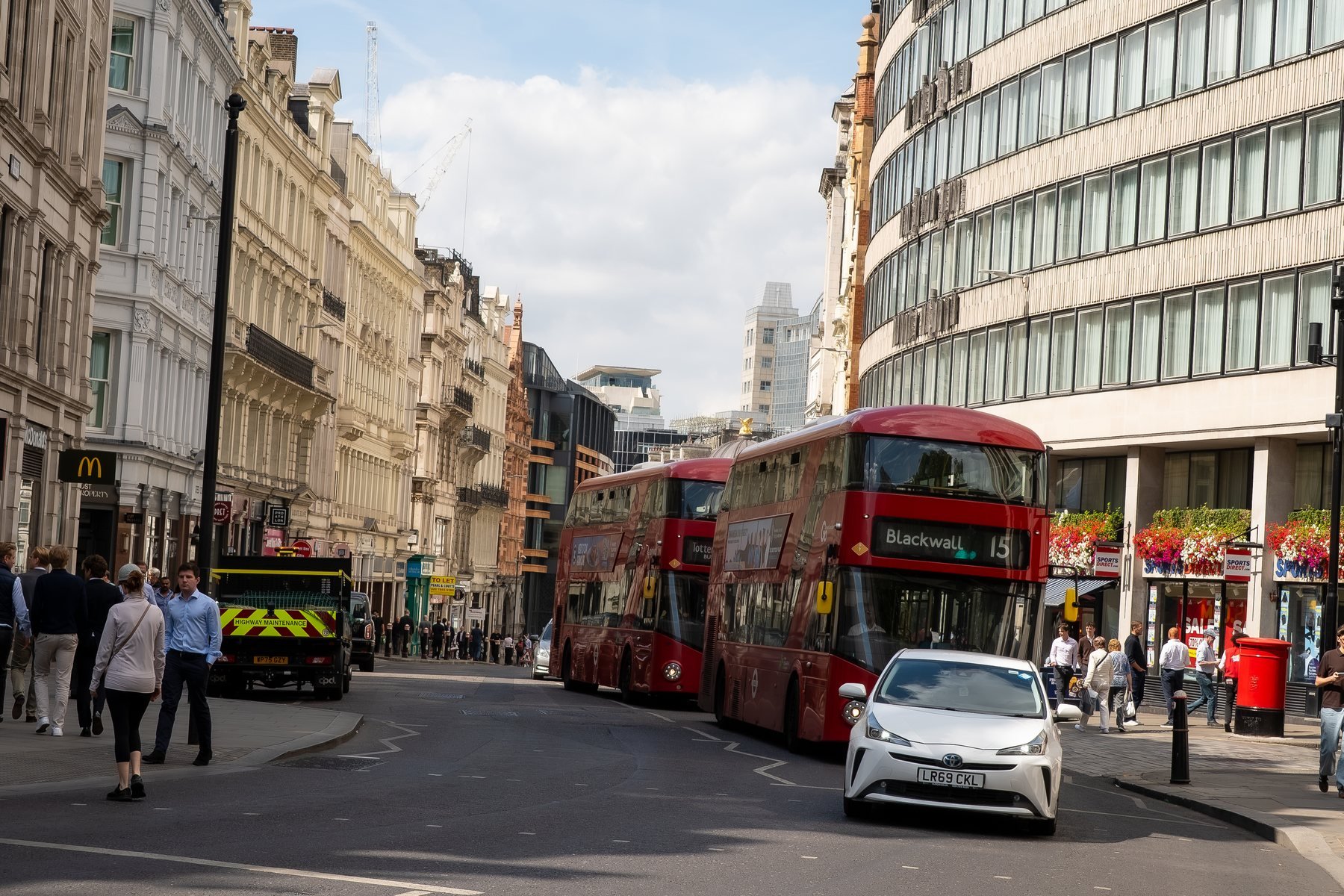 Busy London street with red double-decker buses and pedestrians, street photography