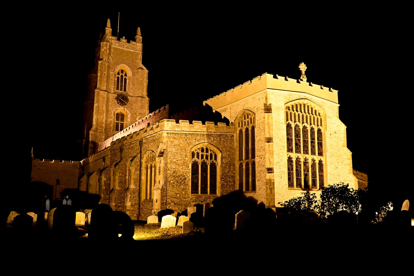 Illuminated Suffolk church tower and nave at night, golden floodlit stonework against a black sky, wall art print