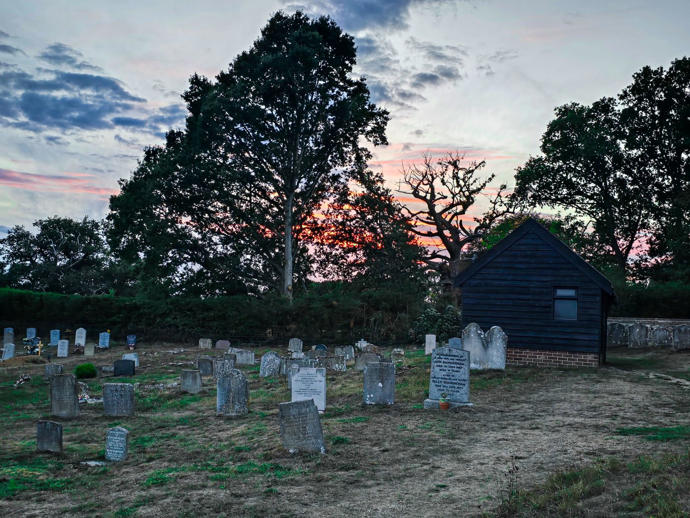 Weathered gravestones in a country churchyard at dusk with a colourful sunset sky, wall art print