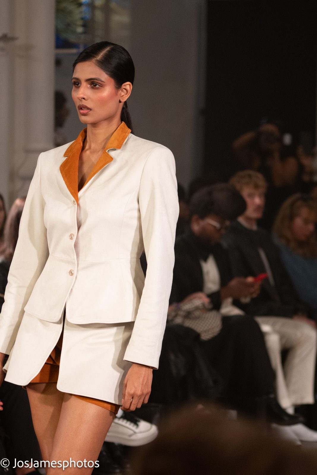 Model in a white tailored jacket with orange lining on the catwalk, London Fashion Week 2026