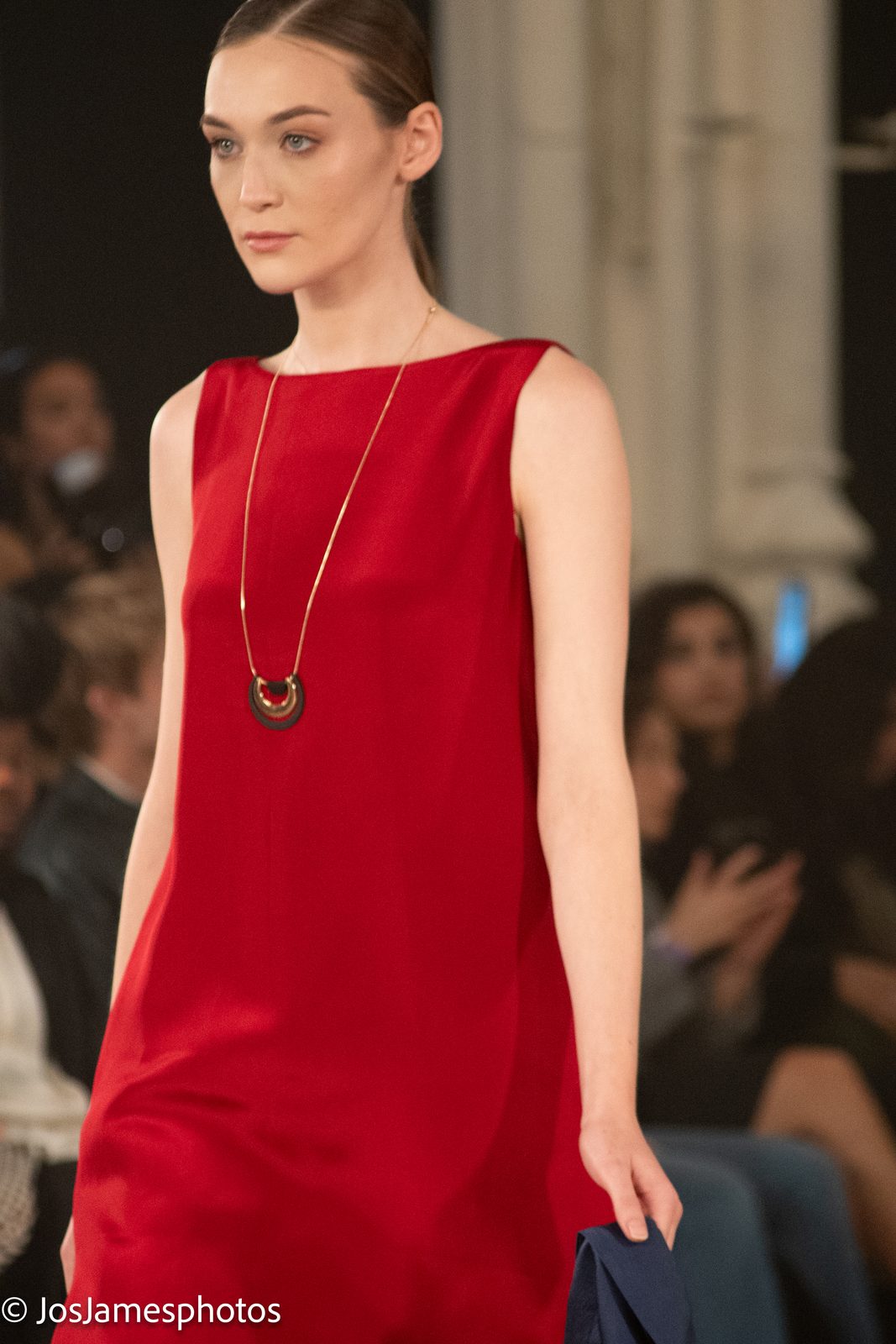 Model in a red shift dress with pendant necklace on the catwalk, London Fashion Week 2026 event photography