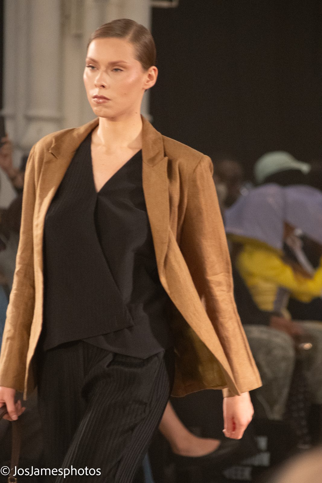Model in a tan jacket and black outfit on the catwalk, London Fashion Week 2026