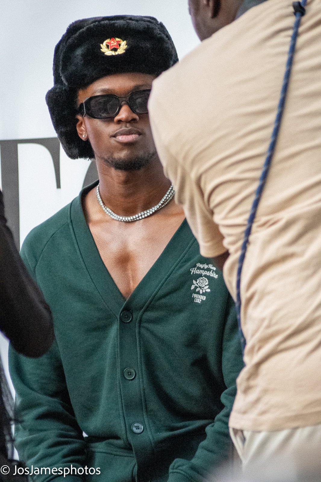 Guest in a black fur trapper hat, sunglasses and green cardigan at the show, London Fashion Week 2026 event photography